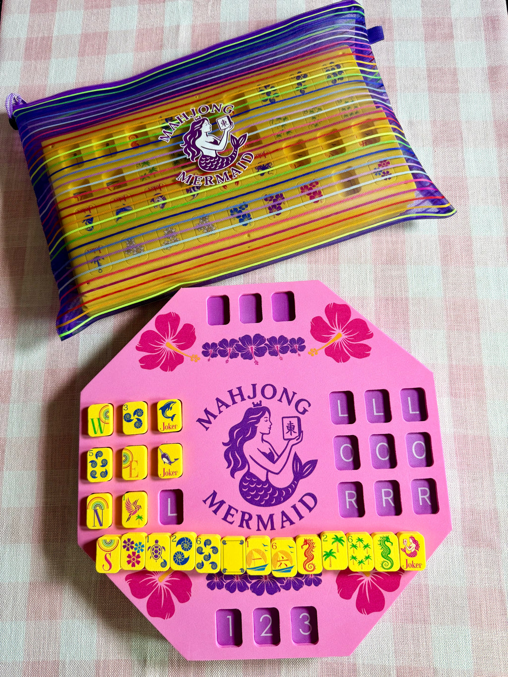 Pink floating solo mahjong mat and yellow floating mahjong tiles with colorful striped mesh tile bag