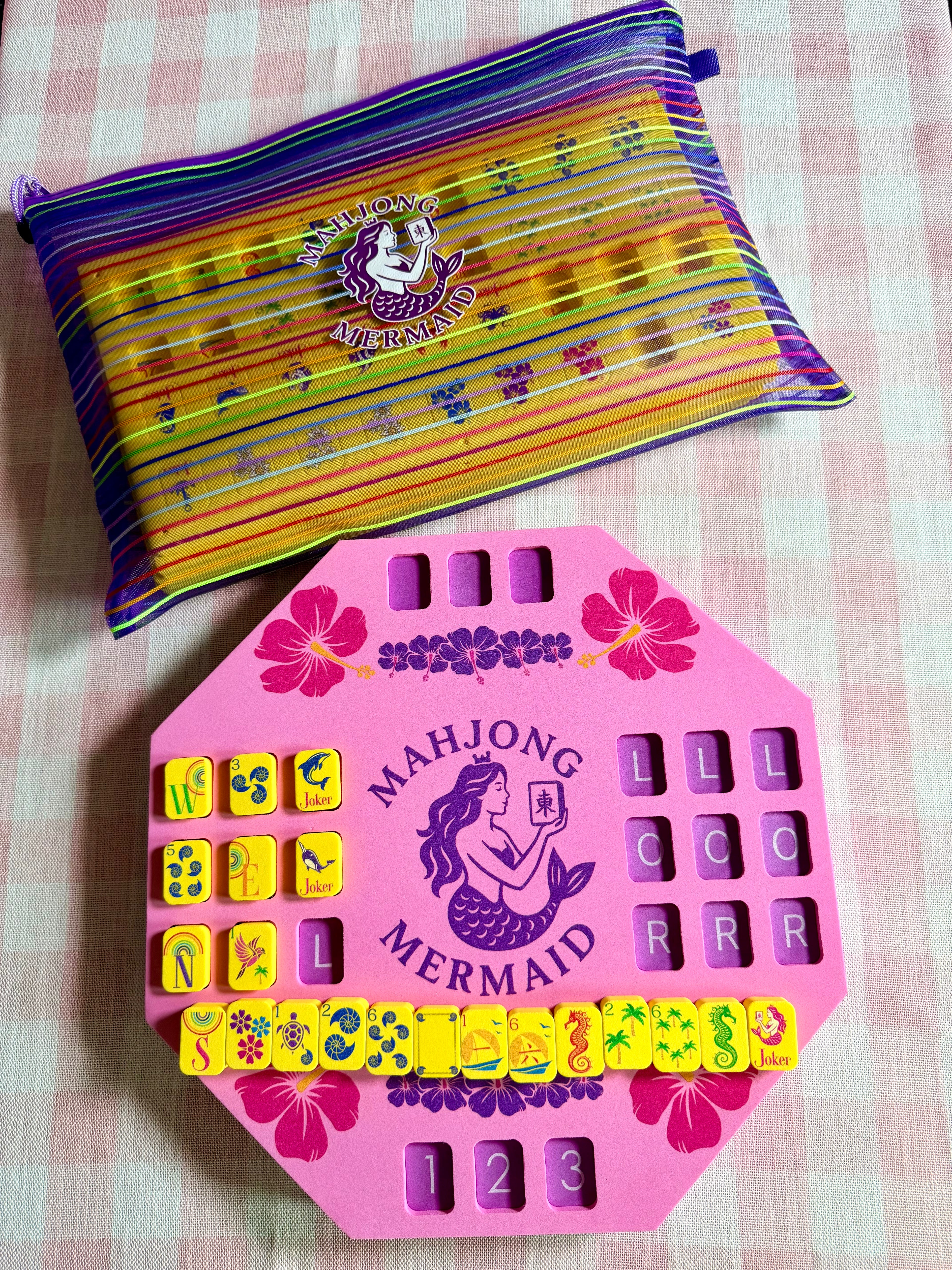 Pink floating solo mahjong mat and yellow floating mahjong tiles with colorful striped mesh tile bag