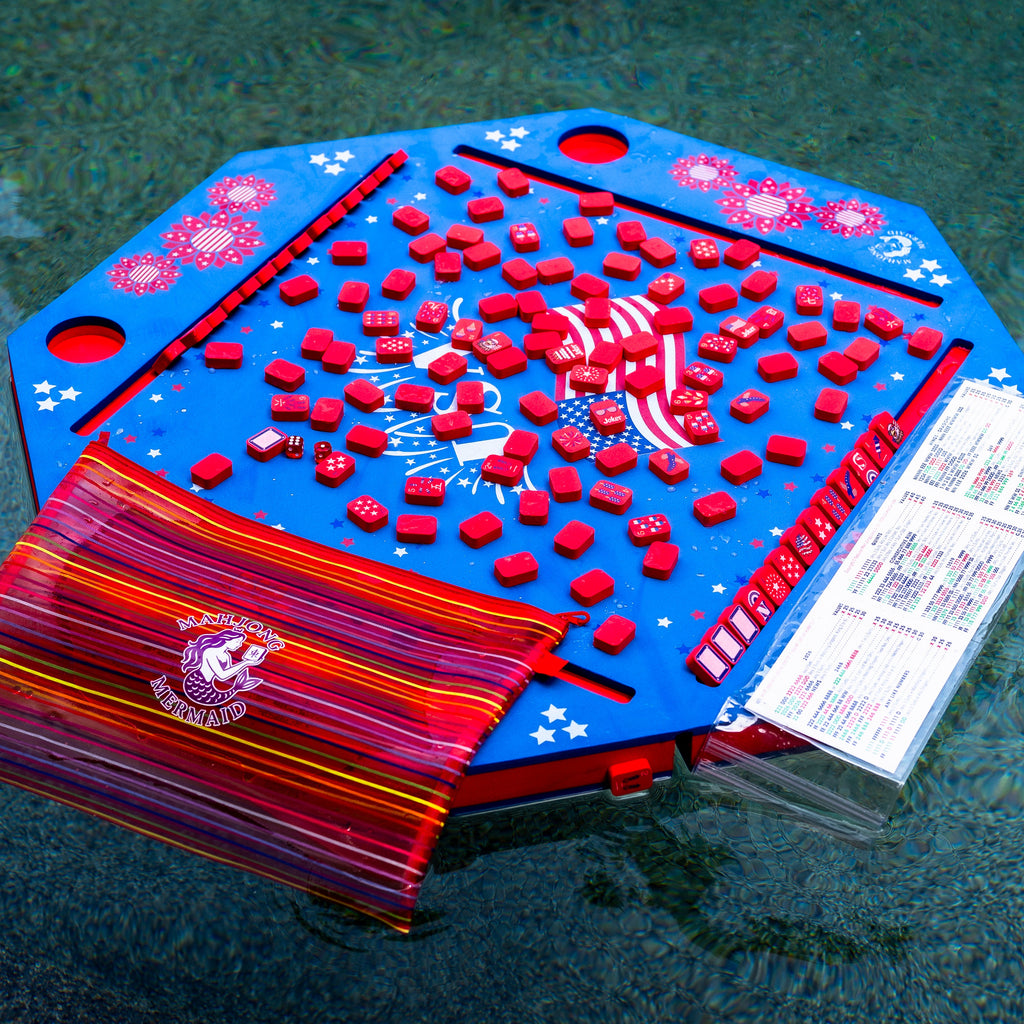Blue patriotic floating mahjong mat with red patriotic mahjong tiles, a red tile bag, and waterproof card cover floating in the pool