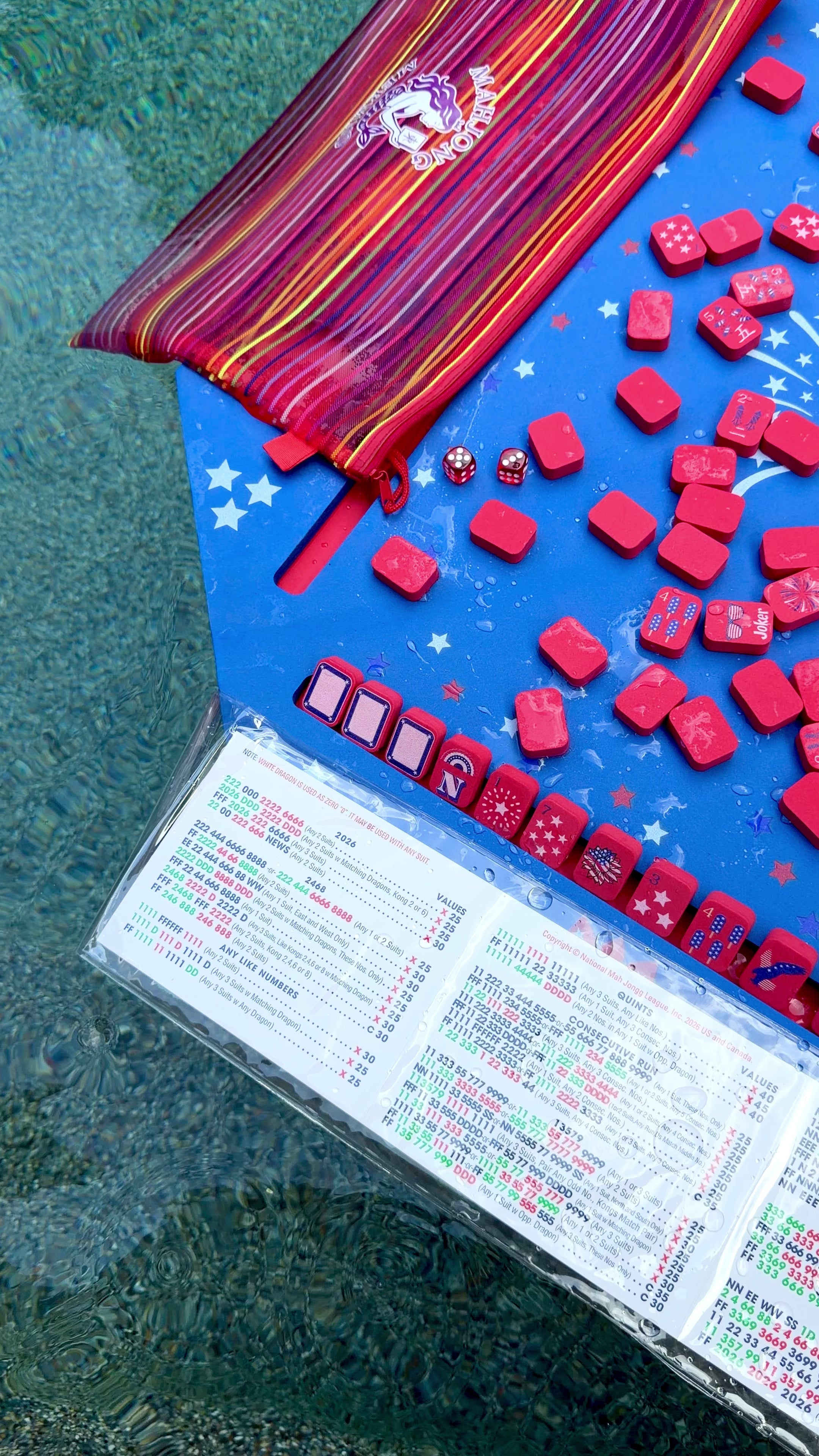Blue patriotic floating mahjong mat with red patriotic mahjong tiles, a red tile bag, and waterproof card cover floating in the pool